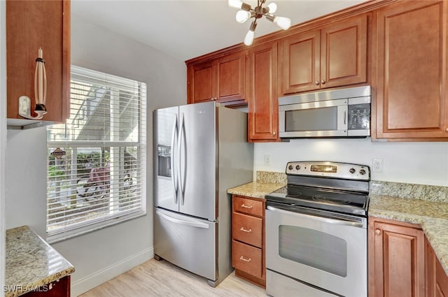 kitchen with light hardwood / wood-style floors, light stone counters, and appliances with stainless steel finishes