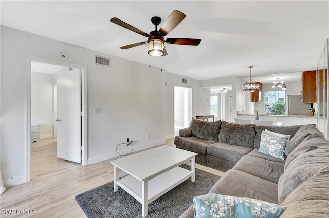 living room featuring ceiling fan with notable chandelier and light hardwood / wood-style floors