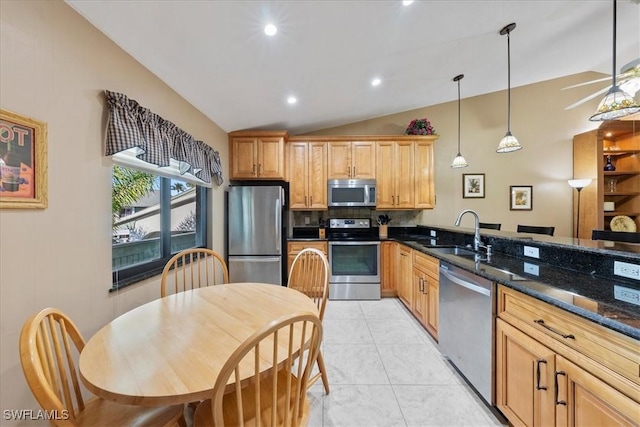 kitchen featuring lofted ceiling, dark stone counters, hanging light fixtures, sink, and stainless steel appliances