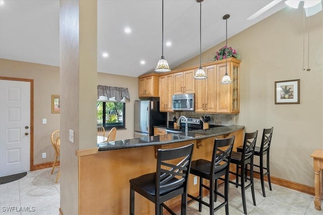 kitchen with a breakfast bar, lofted ceiling, backsplash, appliances with stainless steel finishes, and kitchen peninsula