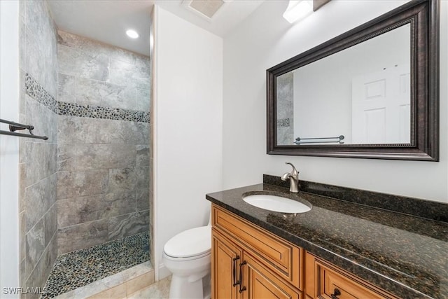 bathroom featuring tiled shower, tile patterned floors, vanity, and toilet