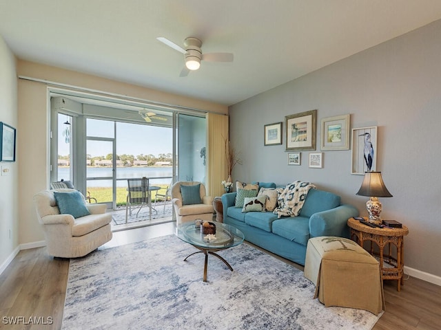 living room featuring hardwood / wood-style floors, ceiling fan, and a water view