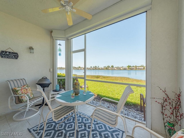 sunroom / solarium with ceiling fan and a water view