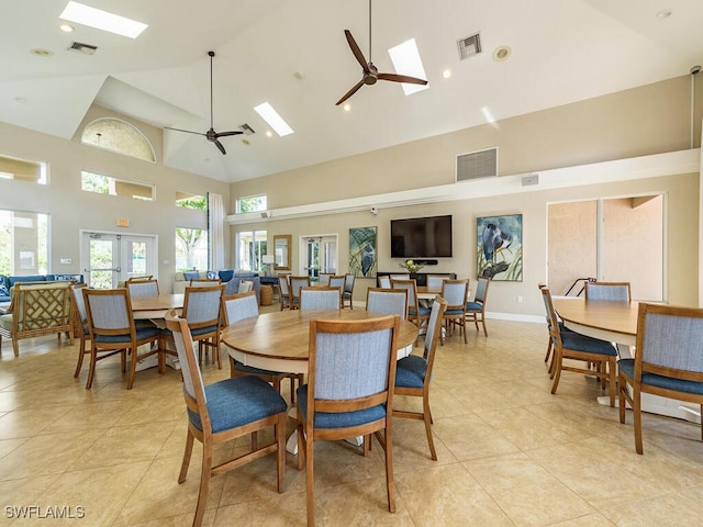 tiled dining area featuring ceiling fan, a skylight, high vaulted ceiling, and french doors