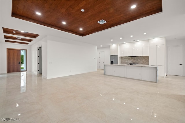 interior space featuring a raised ceiling, stainless steel fridge with ice dispenser, white cabinets, and wood ceiling