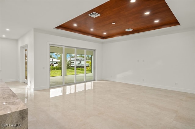 empty room with a raised ceiling and wooden ceiling