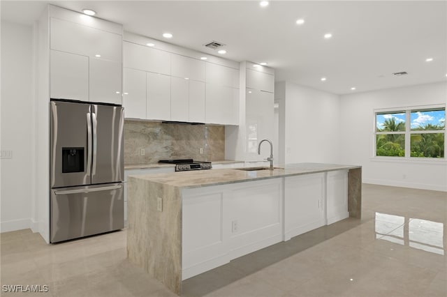 kitchen with sink, tasteful backsplash, stainless steel fridge with ice dispenser, an island with sink, and white cabinets