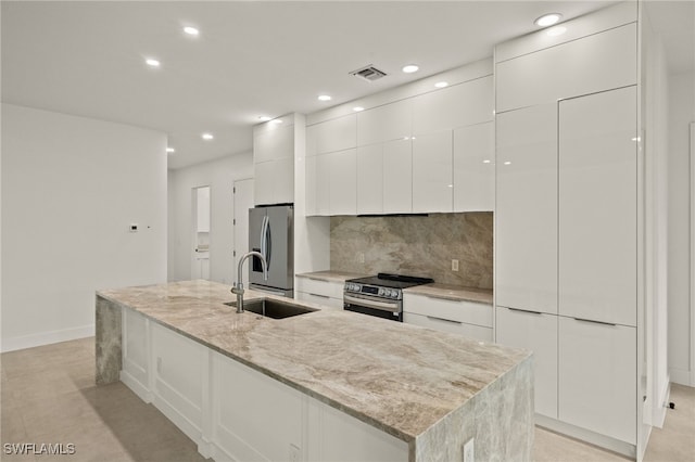 kitchen featuring white cabinets, appliances with stainless steel finishes, a kitchen island with sink, and sink