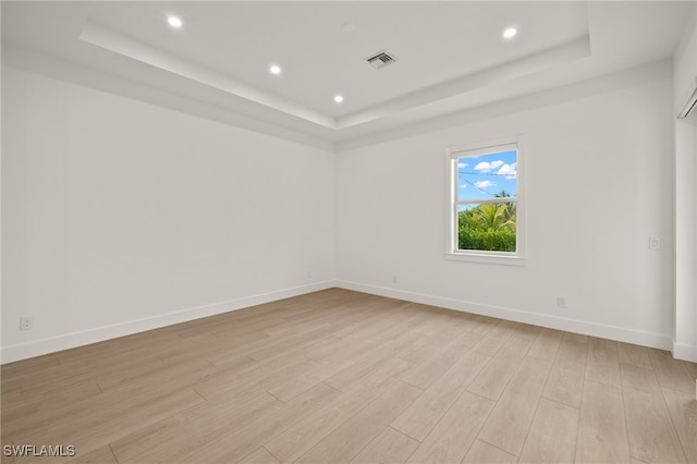 unfurnished room with a tray ceiling and light hardwood / wood-style floors