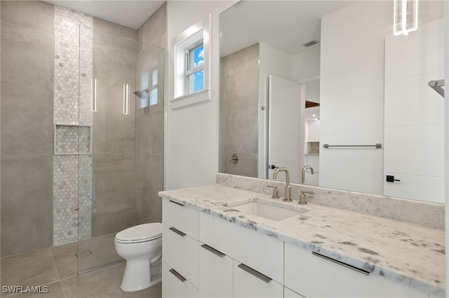 bathroom featuring tile patterned floors, vanity, toilet, and a shower with door