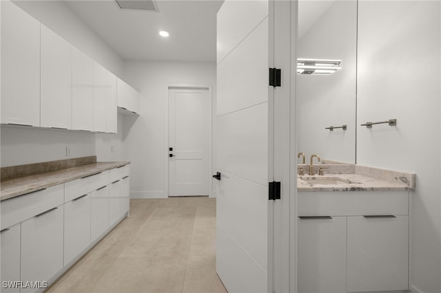 interior space featuring white cabinetry, sink, and light stone counters