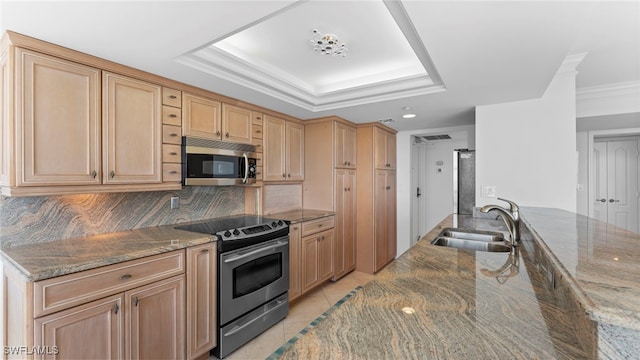 kitchen with dark stone countertops, sink, light tile patterned floors, and stainless steel appliances