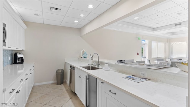 kitchen featuring white cabinets, stainless steel dishwasher, light stone counters, and sink