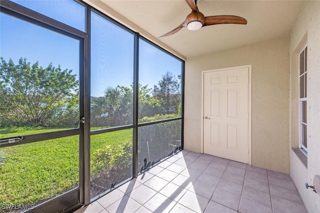 unfurnished sunroom featuring ceiling fan and a wealth of natural light