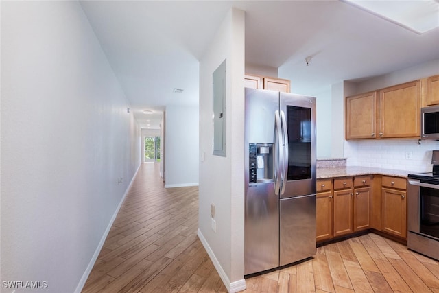 kitchen featuring light hardwood / wood-style floors, light stone counters, backsplash, and appliances with stainless steel finishes