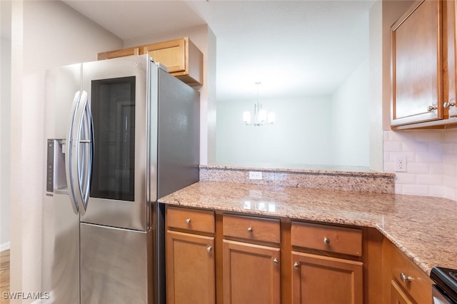 kitchen with an inviting chandelier, tasteful backsplash, decorative light fixtures, kitchen peninsula, and stainless steel appliances