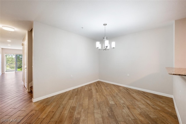 unfurnished dining area with an inviting chandelier and hardwood / wood-style flooring