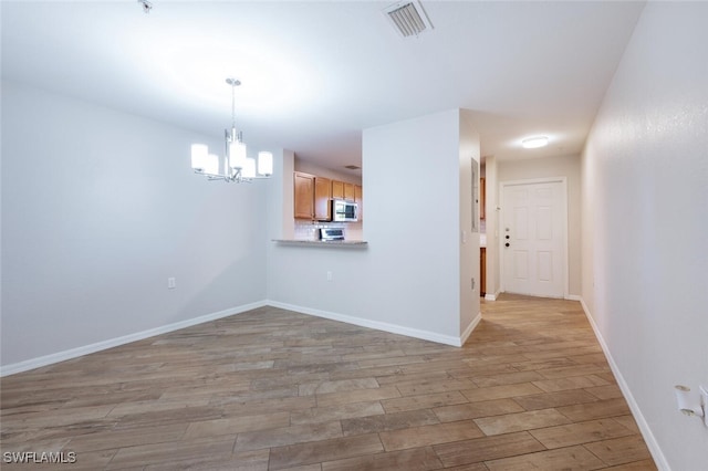 interior space featuring a notable chandelier and light wood-type flooring