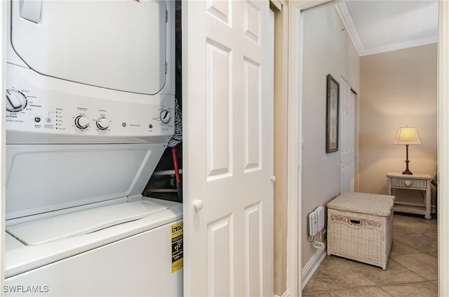 washroom featuring crown molding, light tile patterned flooring, and stacked washer and clothes dryer