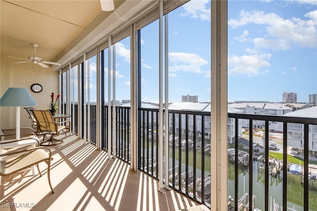 unfurnished sunroom with ceiling fan and a water view