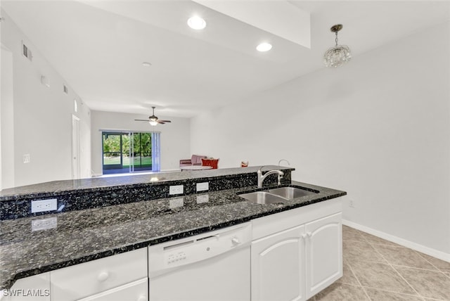 kitchen with white dishwasher, white cabinets, sink, hanging light fixtures, and dark stone countertops