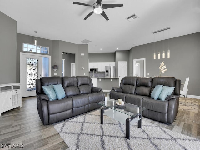 living room with ceiling fan and light wood-type flooring