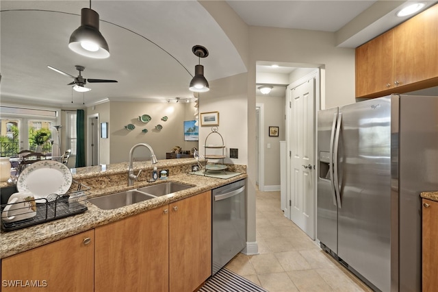 kitchen featuring light stone counters, stainless steel appliances, ceiling fan, sink, and hanging light fixtures