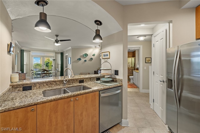 kitchen featuring light stone countertops, stainless steel appliances, ceiling fan, and sink