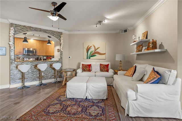 living room with hardwood / wood-style flooring, ceiling fan, crown molding, and sink