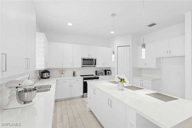 kitchen featuring appliances with stainless steel finishes, decorative light fixtures, and white cabinetry