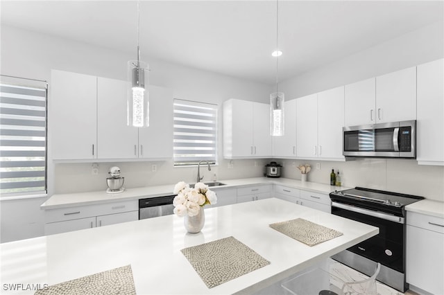 kitchen with white cabinets, sink, decorative light fixtures, a kitchen bar, and stainless steel appliances