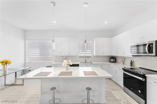 kitchen featuring a breakfast bar, white cabinetry, hanging light fixtures, and stainless steel appliances