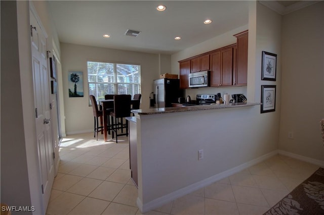 kitchen featuring kitchen peninsula, crown molding, light tile patterned floors, and appliances with stainless steel finishes