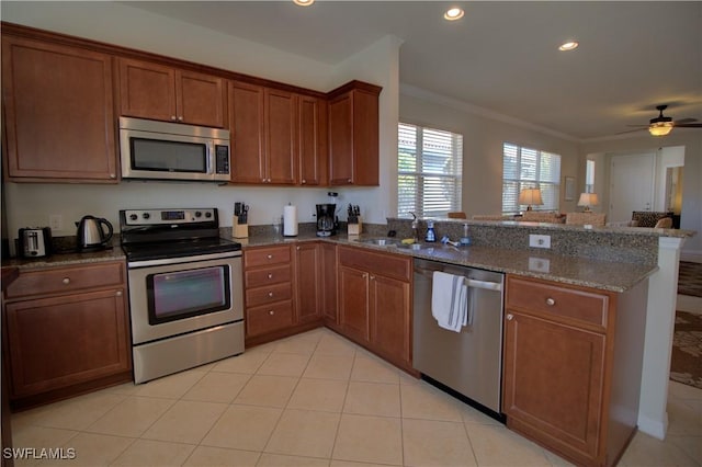 kitchen with ceiling fan, sink, dark stone countertops, appliances with stainless steel finishes, and ornamental molding