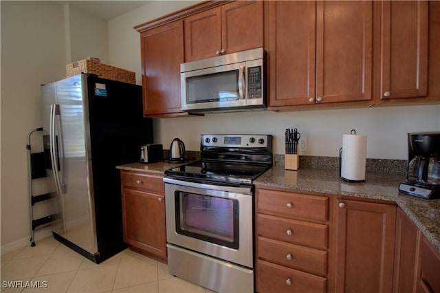 8748 Querce Ct S, Naples, FL 34114 - kitchen with stainless steel appliances, brown cabinets, dark stone countertops, and light tile patterned floors