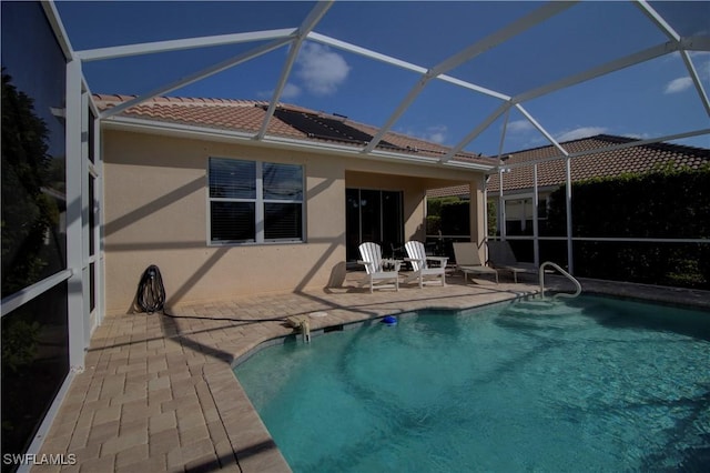 back of property featuring glass enclosure and a patio