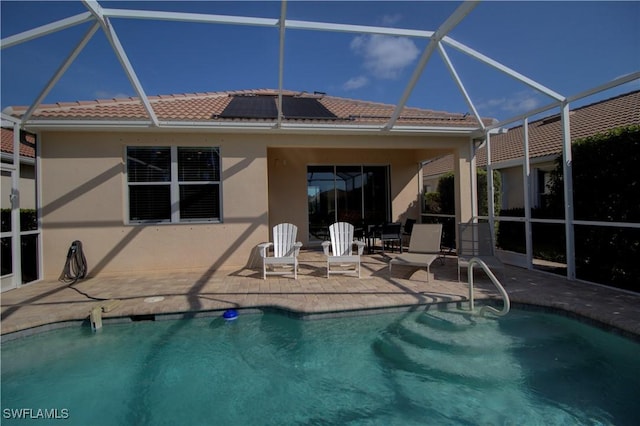 back of house with solar panels, a patio area, and glass enclosure