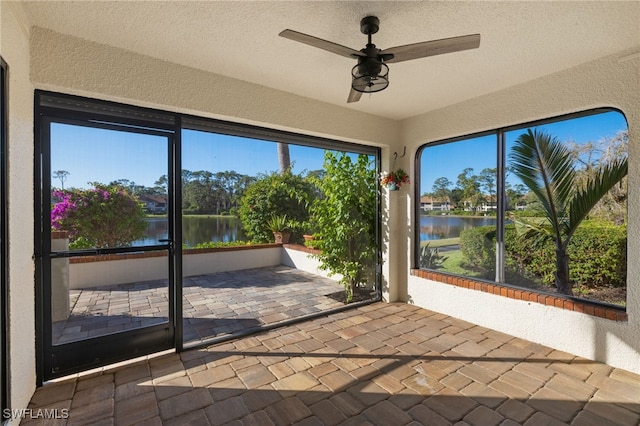 unfurnished sunroom with ceiling fan and a water view