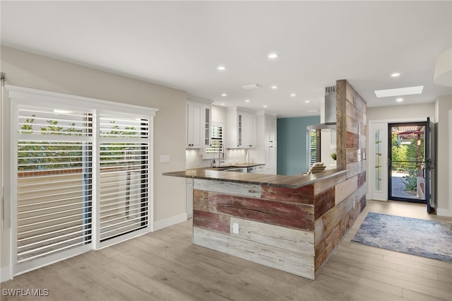 interior space featuring white cabinets, light wood-type flooring, a skylight, and a wealth of natural light