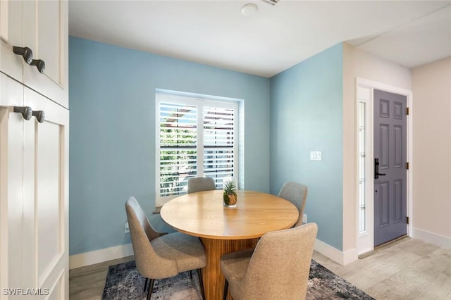 dining space featuring light wood-style floors and baseboards