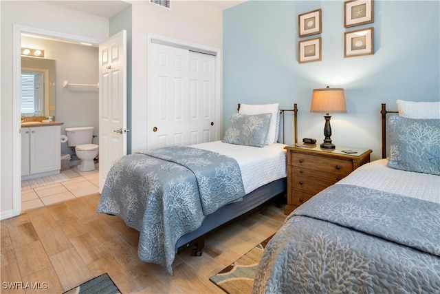 bedroom featuring light hardwood / wood-style floors, ensuite bath, a closet, and sink