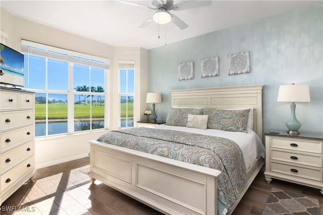 bedroom with ceiling fan, a water view, and dark wood-type flooring