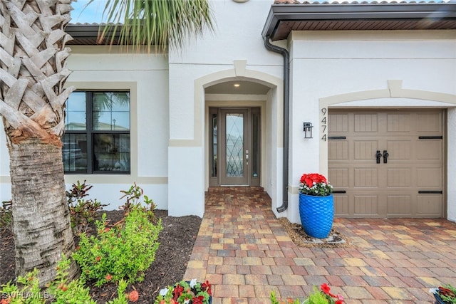 doorway to property with an attached garage and stucco siding