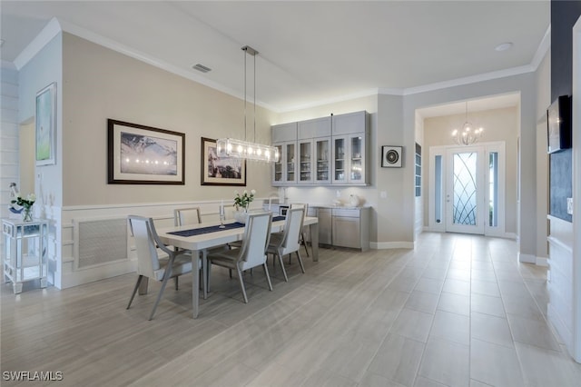 dining space featuring baseboards, visible vents, a chandelier, and ornamental molding