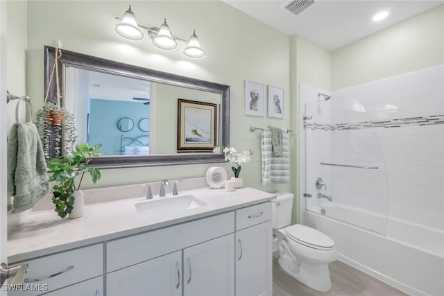 full bathroom featuring vanity, wood-type flooring, tiled shower / bath combo, and toilet