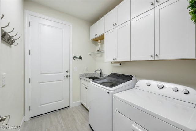 laundry room featuring washing machine and clothes dryer, a sink, cabinet space, and baseboards