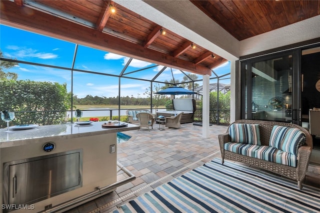 view of patio / terrace featuring a lanai, an outdoor living space, area for grilling, and a water view