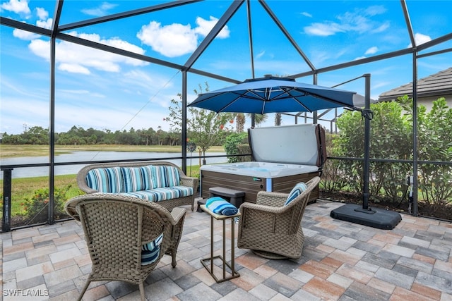 view of patio / terrace featuring a lanai, a water view, and a hot tub