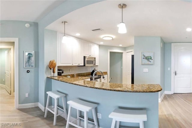 kitchen featuring white cabinets, pendant lighting, stainless steel appliances, and kitchen peninsula