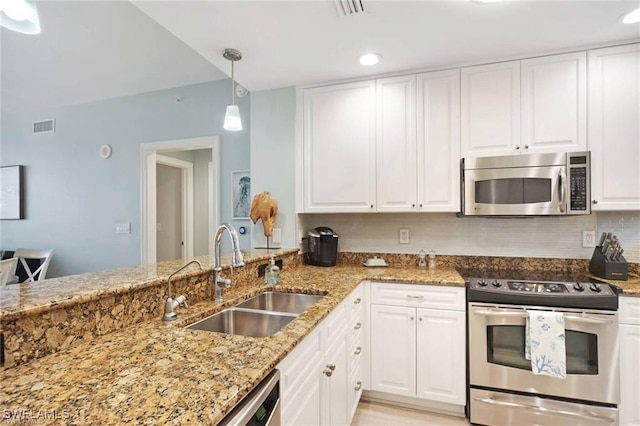 kitchen with light stone countertops, sink, hanging light fixtures, stainless steel appliances, and white cabinets